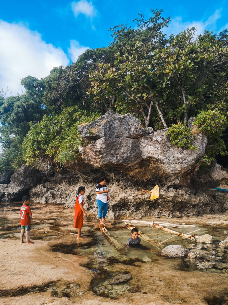 Tongan kids playing with a raft in the ocean at low tide on 'Eua, Tonga
