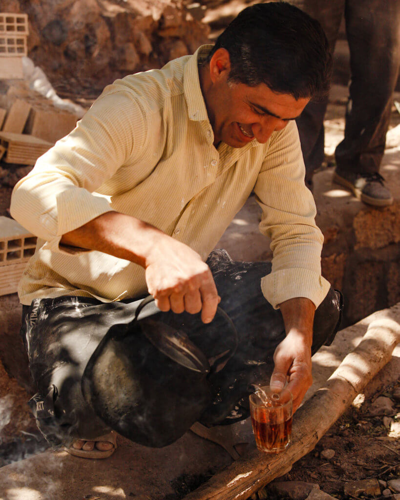 Iranian man making tea in Abyaneh as part of your Iran travel itinerary