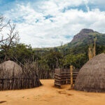 A traditional Swazi hut surrounded by lush greenery in Eswatini.